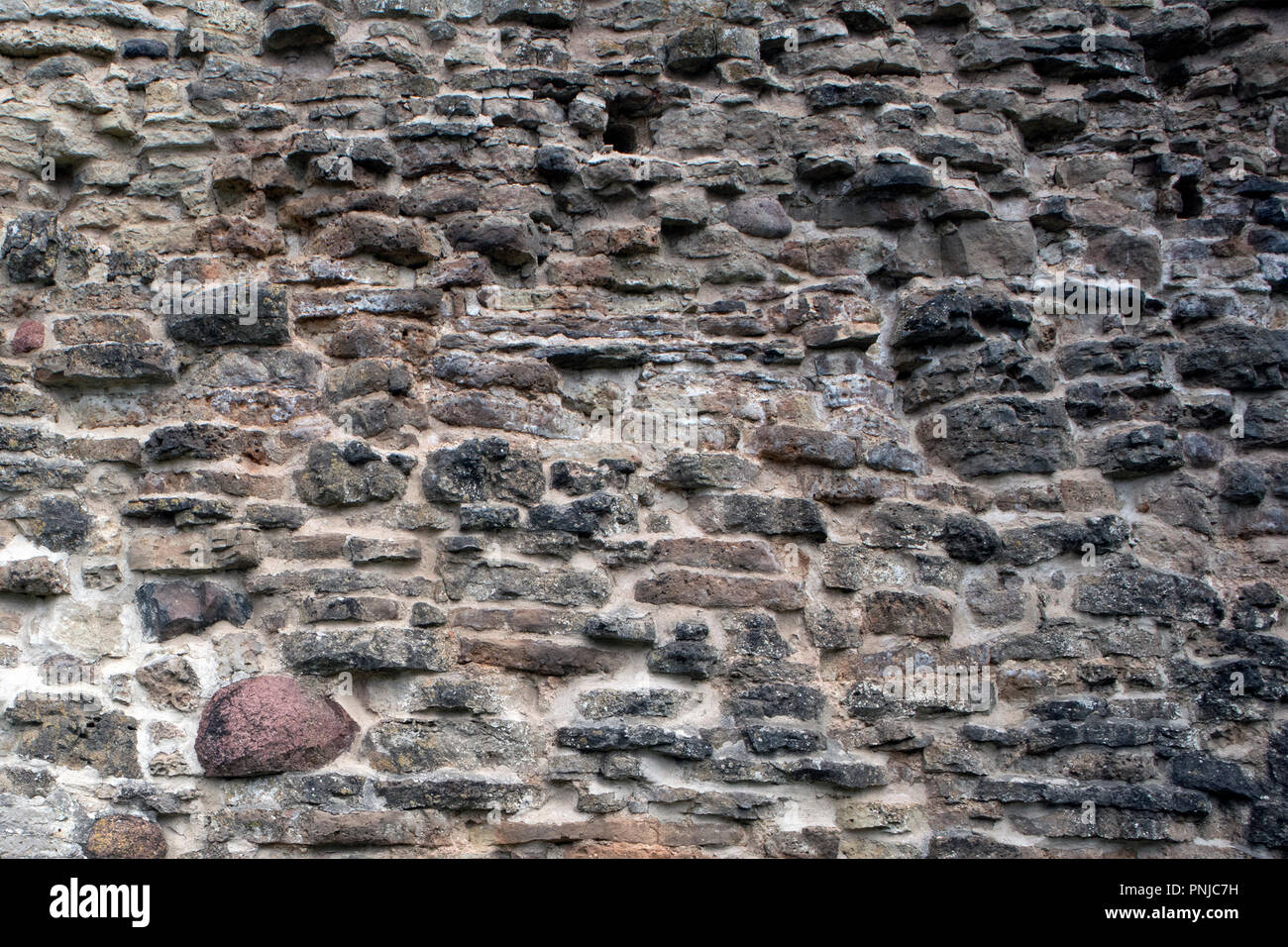 La texture de la maçonnerie, fragment de l'ancienne forteresse en ruine de mur de briques et de pierres de granit Banque D'Images