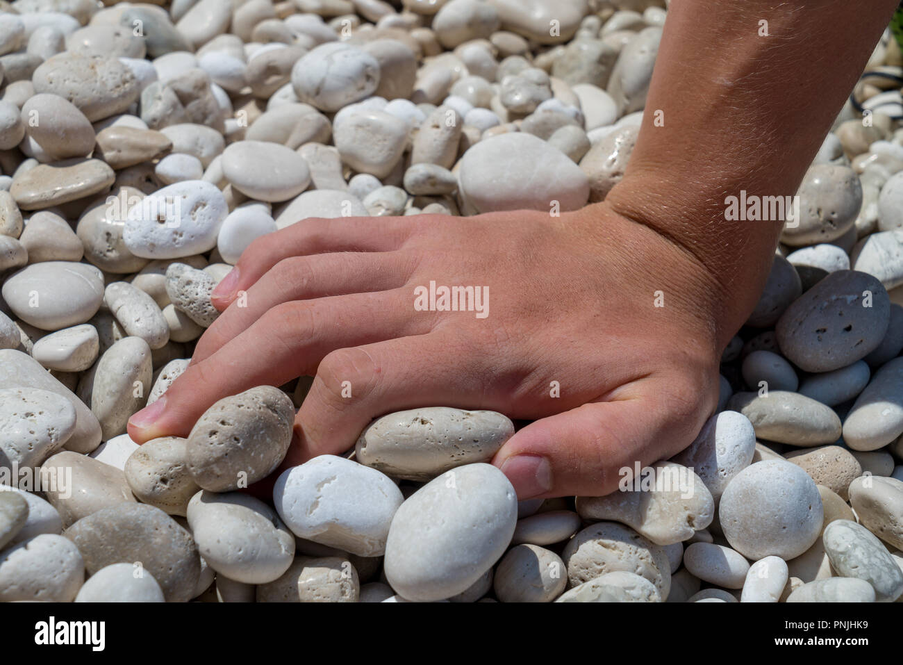 Gros plan d'une main sur une plage de galets Banque D'Images