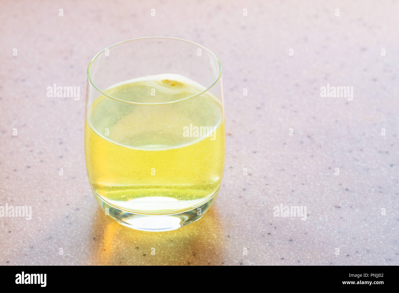 Comprimé jaune de vitamine C se dissout dans de l'eau Banque D'Images