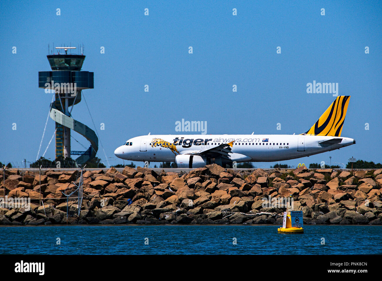Sydney, Nouvelle-Galles du Sud, Australie - Novembre 7. 2013 : Tiger Airways avion à réaction commerciaux de passagers l'imposition au-delà de la tour de contrôle. Banque D'Images
