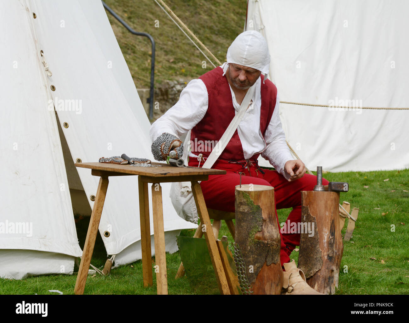 TONBRIDGE, Angleterre - le 8 septembre 2018 : l'homme habillé dans des vêtements du Moyen Age stamps des morceaux de métal pour en faire armor à la Foire Médiévale, tenue Banque D'Images