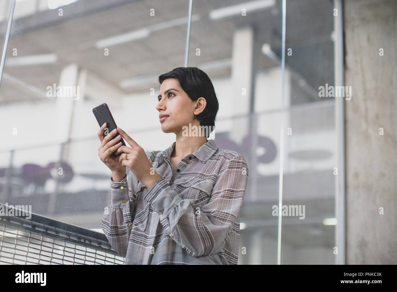 Femme arabe à l'aide d'un smartphone dans un bureau Banque D'Images