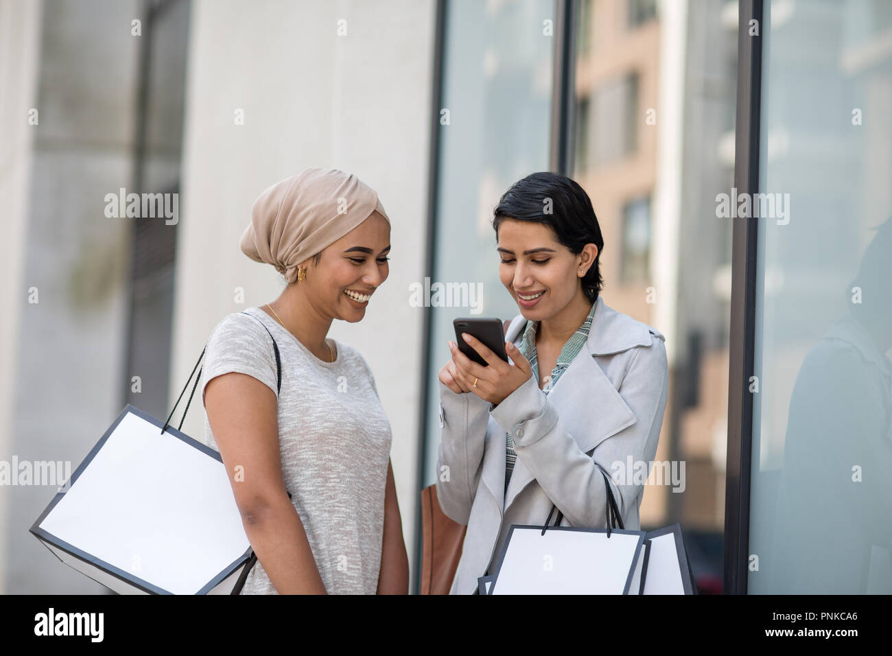 Amis musulmans à l'aide d'un smartphone sur un voyage de shopping Banque D'Images