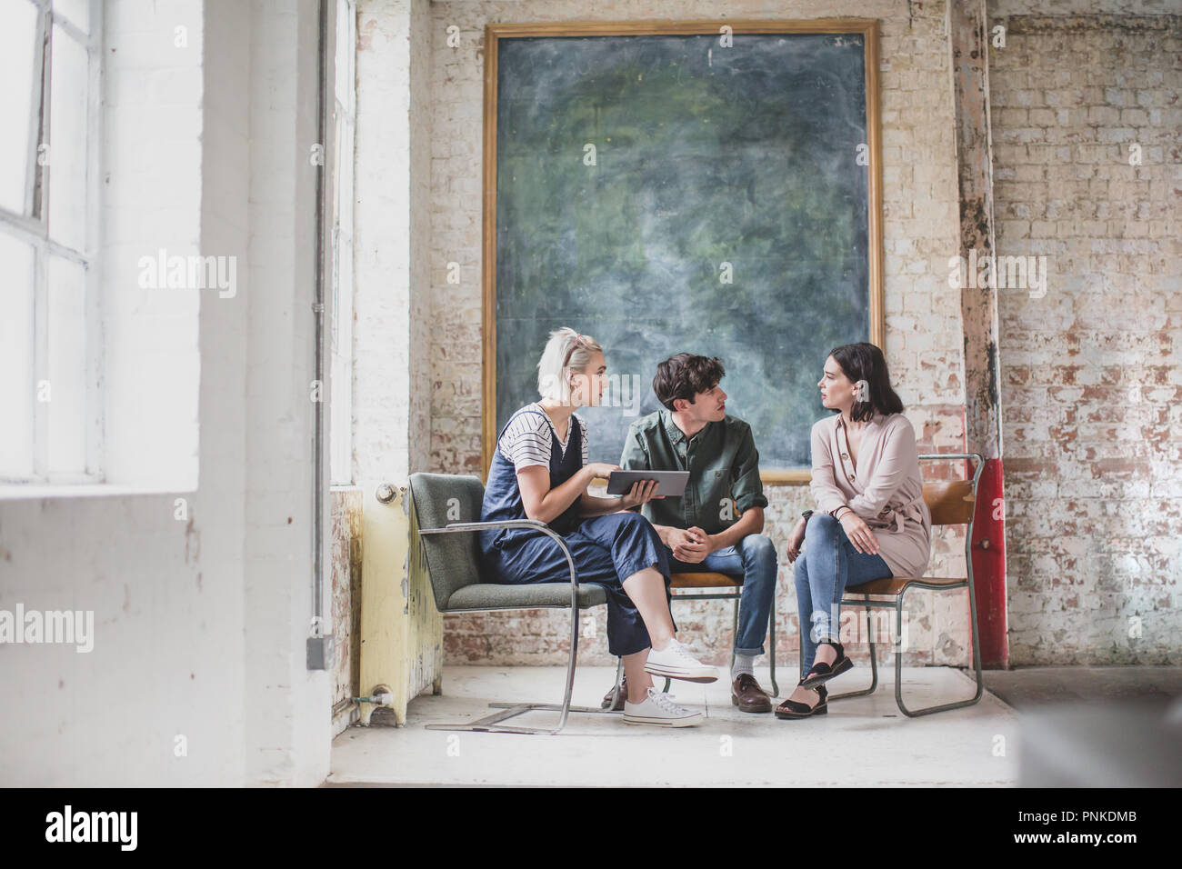 Les jeunes adultes lors d'une rencontre dans un studio de création avec une tablette numérique Banque D'Images