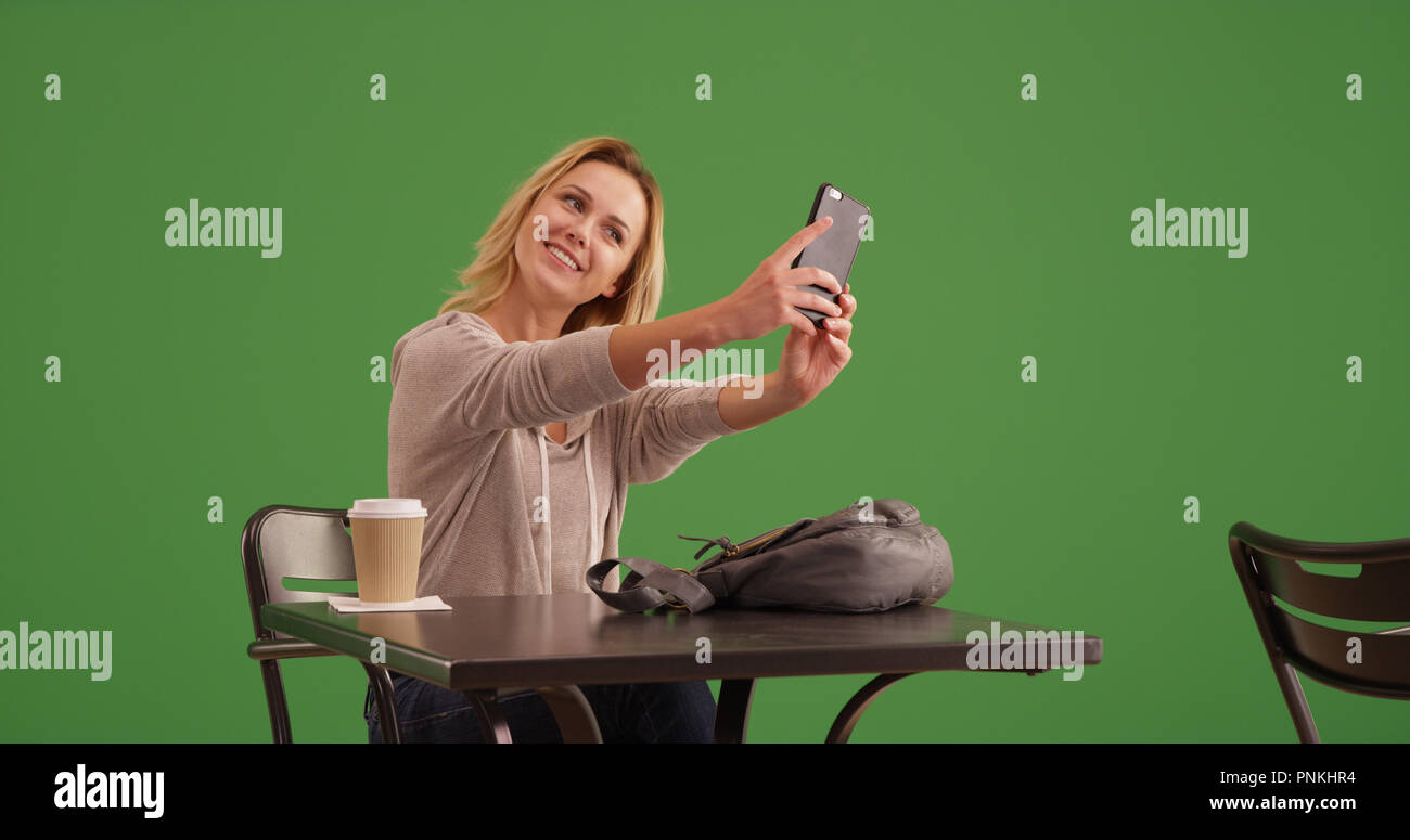 Femme blanche prendre photo tout en selfies at coffee shop sur écran vert Banque D'Images