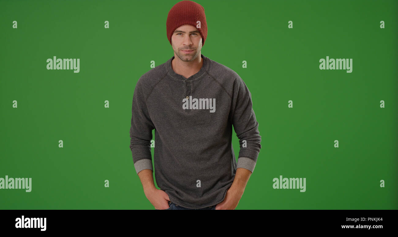 Handsome man wearing white beanie posant avec les mains dans les poches sur un écran vert Banque D'Images