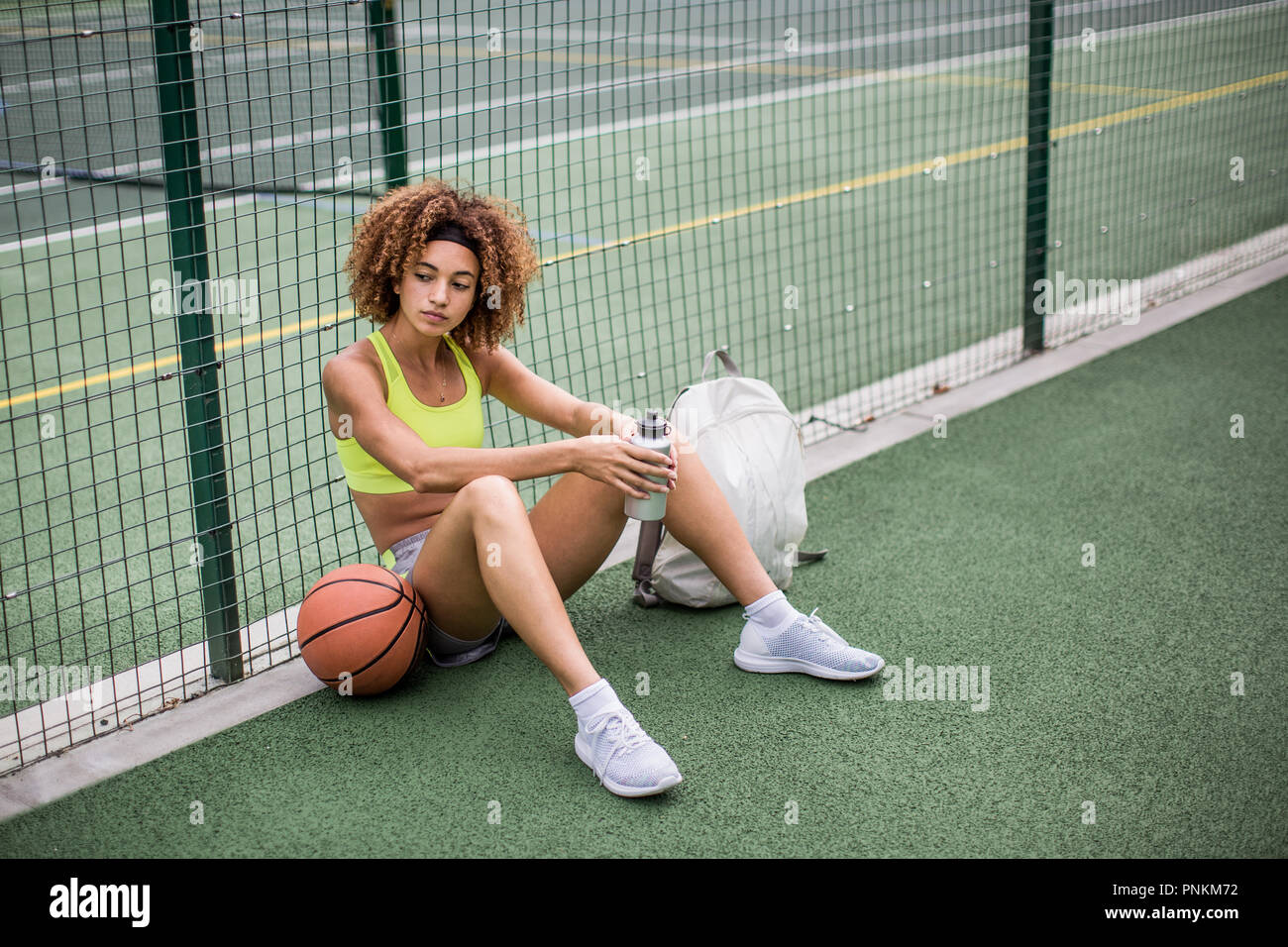 Les jeunes femelles adultes assis sur un terrain de basket-ball Banque D'Images