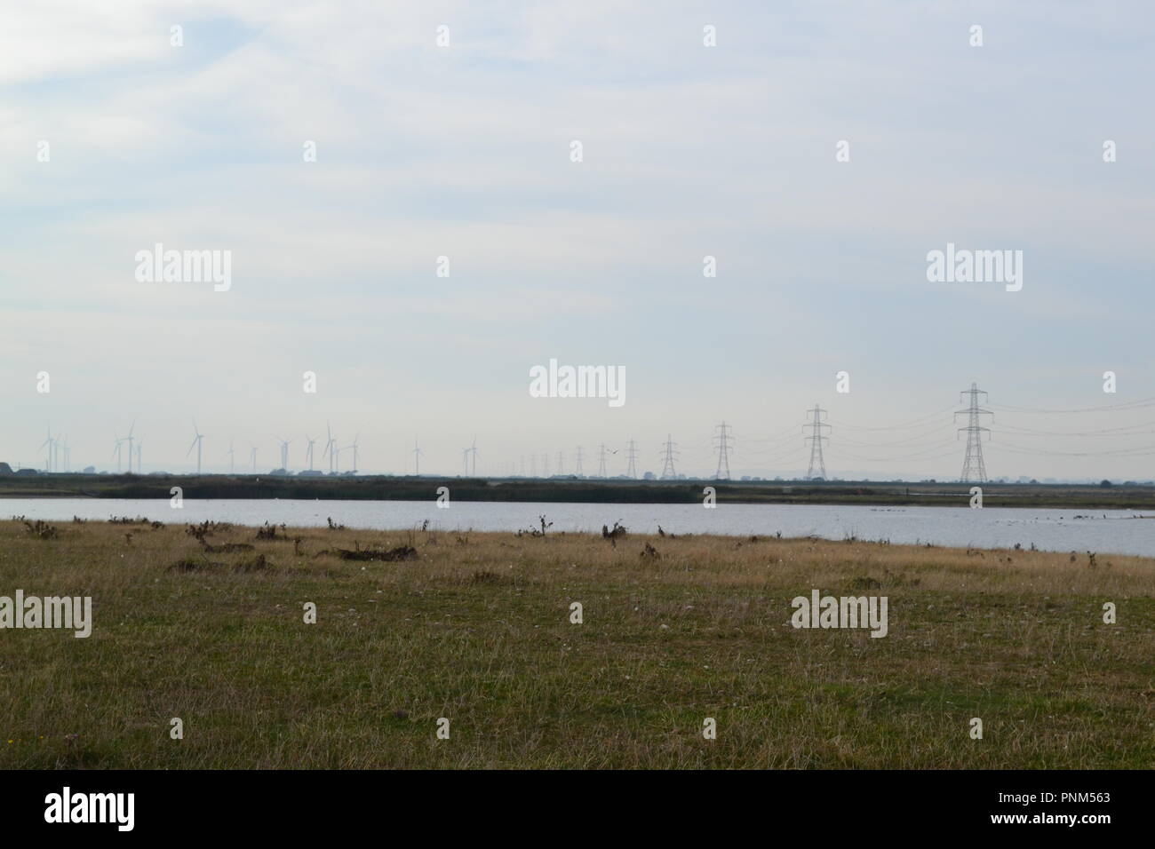 Pylônes électriques et un lac à Camber, East Sussex, England, UK Banque D'Images