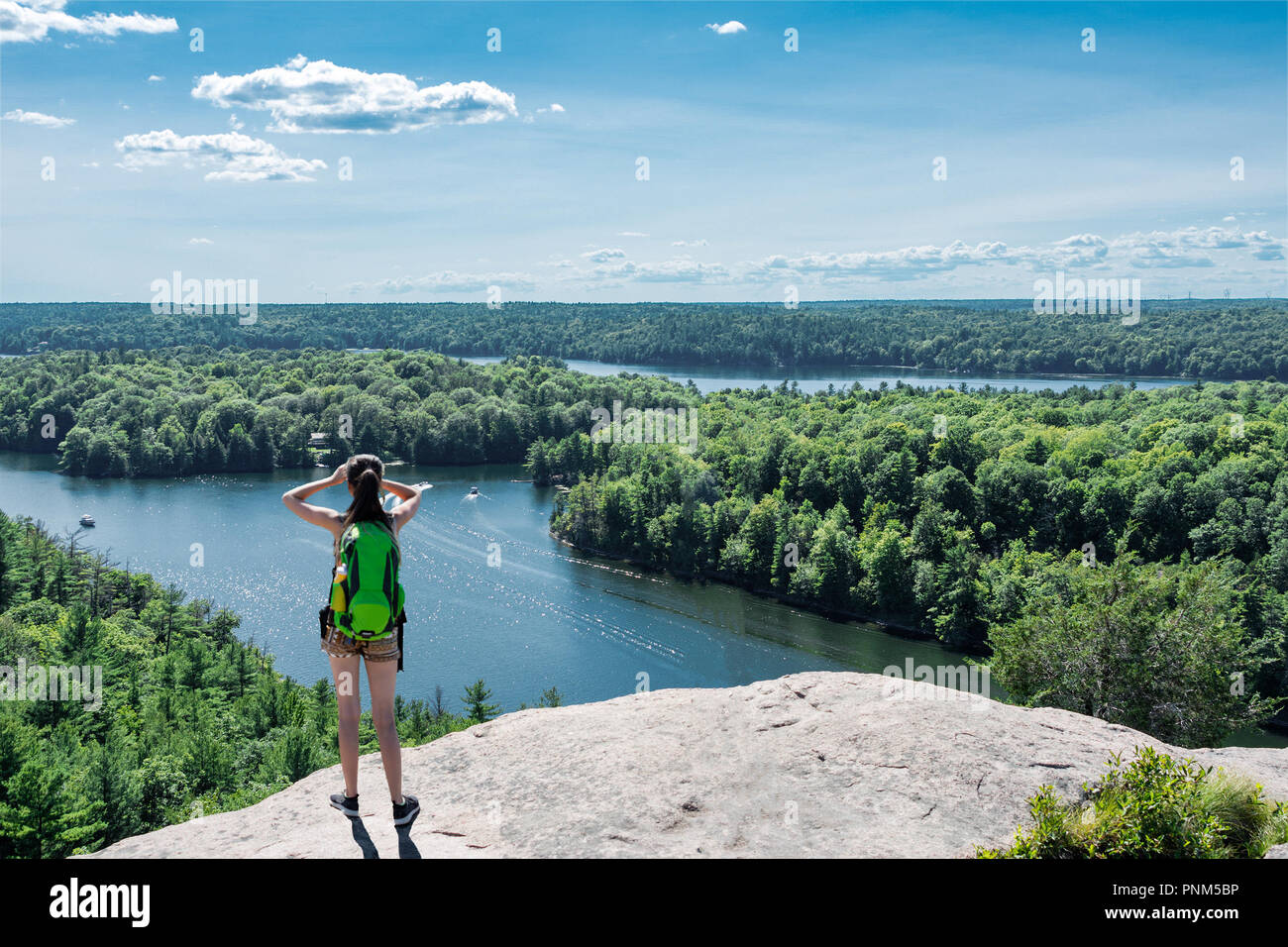 La fille se tient avec les jumelles en haut de la montagne, et ci-dessous sont grandes, lacs bleus avec de l'eau claire et transparente Banque D'Images