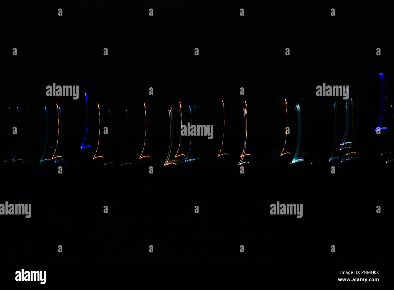 Des sentiers de lumière d'obturation lente avec un arrière-plan sombre. Ceci a été créé en secouant l'appareil photo en mode lampe Banque D'Images