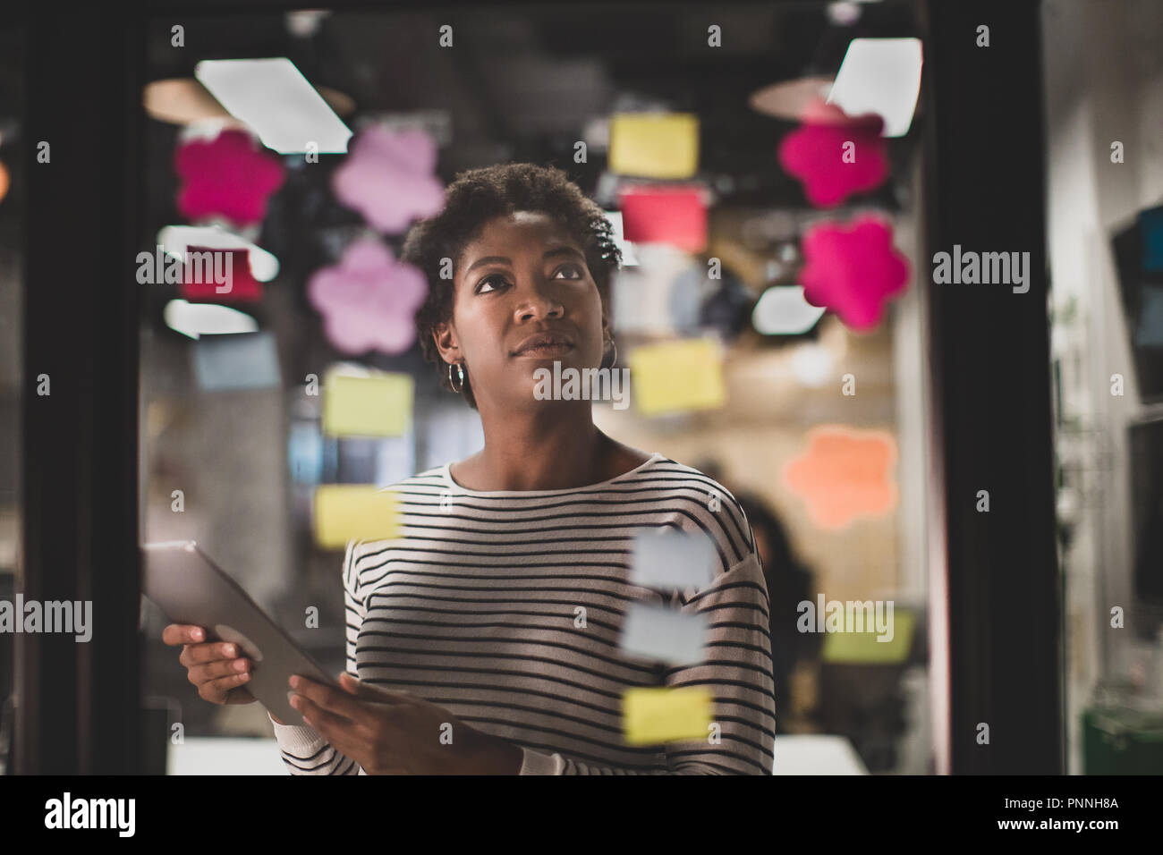 African American female remue-méninges dans la nuit dans un bureau Banque D'Images African American female remue-méninges dans la nuit dans un bureau Banque D'Images