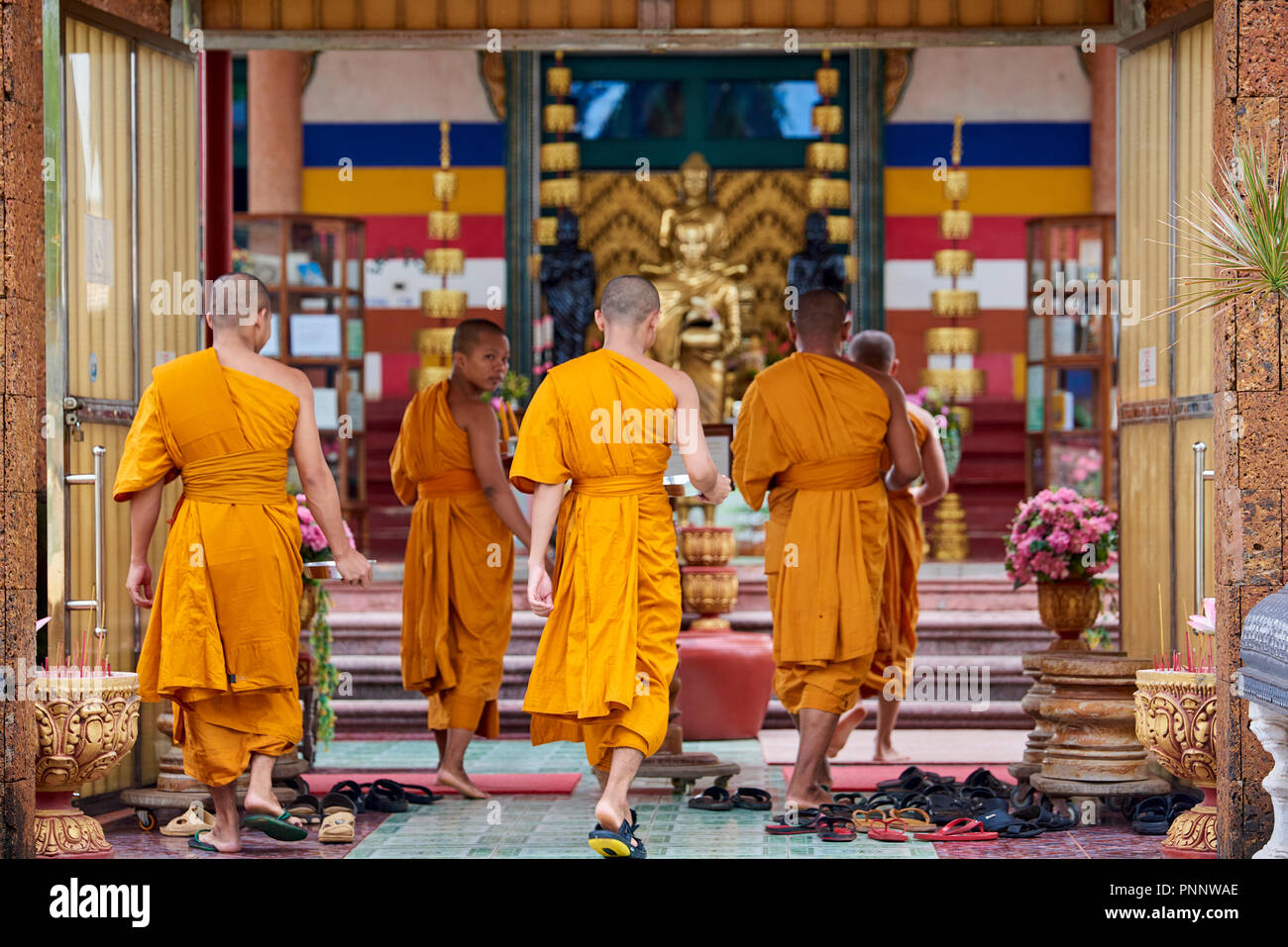 Un groupe de jeunes moines bouddhistes portant des robes orange à marcher vers un lieu de culte avant leurs prières du soir à Phnom Penh, Cambodge. Banque D'Images