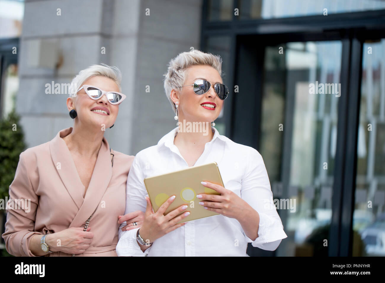 Deux businesswoman walking on street près du bâtiment. Femme d'affaires allant de pair avec l'ordinateur tablette Banque D'Images