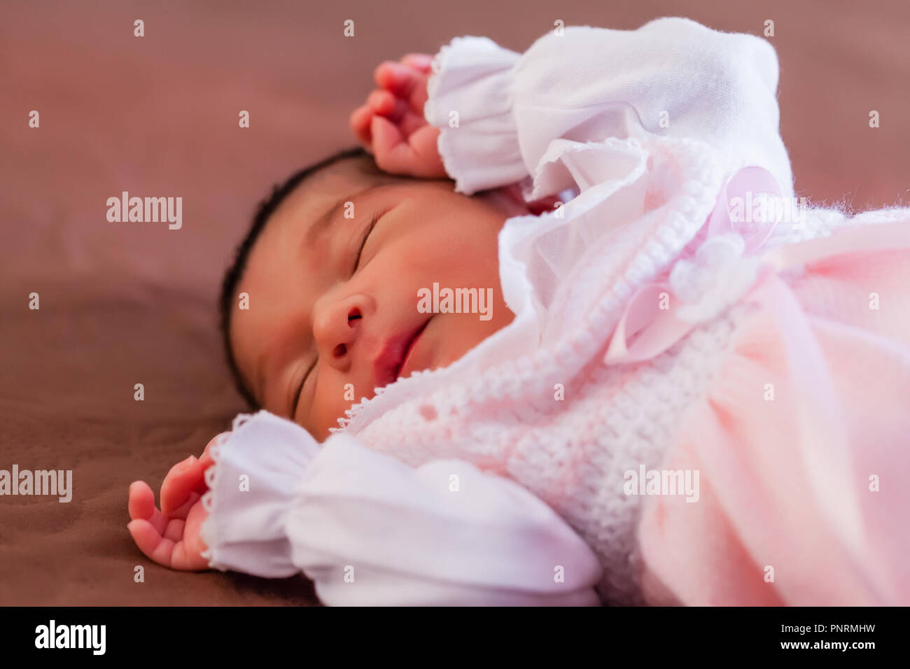 Deux semaines au nouveau-né cute baby girl rose doux vêtements tricotés, dormir paisiblement dans le lit Banque D'Images