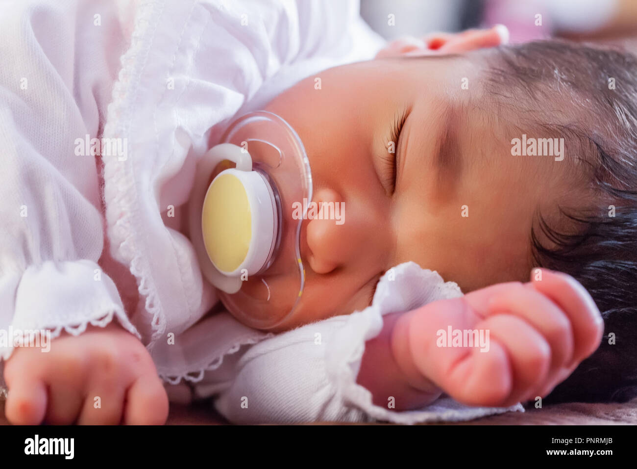 Close up portrait of a cute deux semaines Naissance bebe Fille portant des vêtements en tricot rose tendre, dormir paisiblement avec une tétine, sucette ou factice aka Banque D'Images