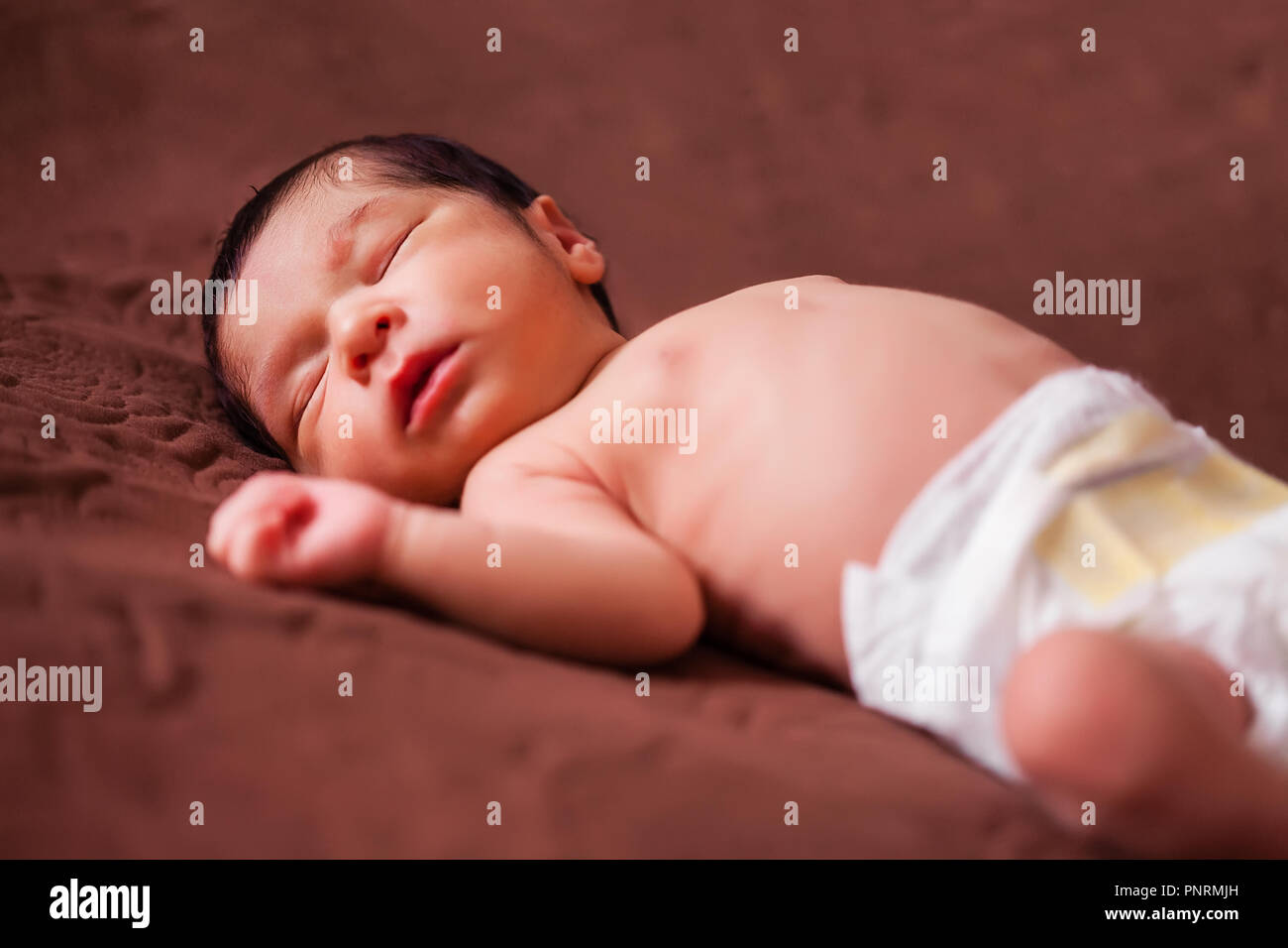 Un mignon deux semaines Naissance bebe Fille sans vêtements, nu ou nue, à l'aide d'une couche ou nappy, dormir paisiblement dans le lit Banque D'Images