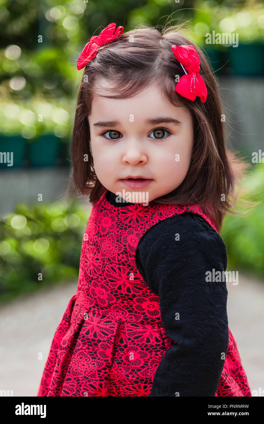 Mignon, joli, heureux, sourire tout-petit baby girl, la modélisation avec un sourire espiègle avec un élégant costume noir et rouge. 24 mois Banque D'Images