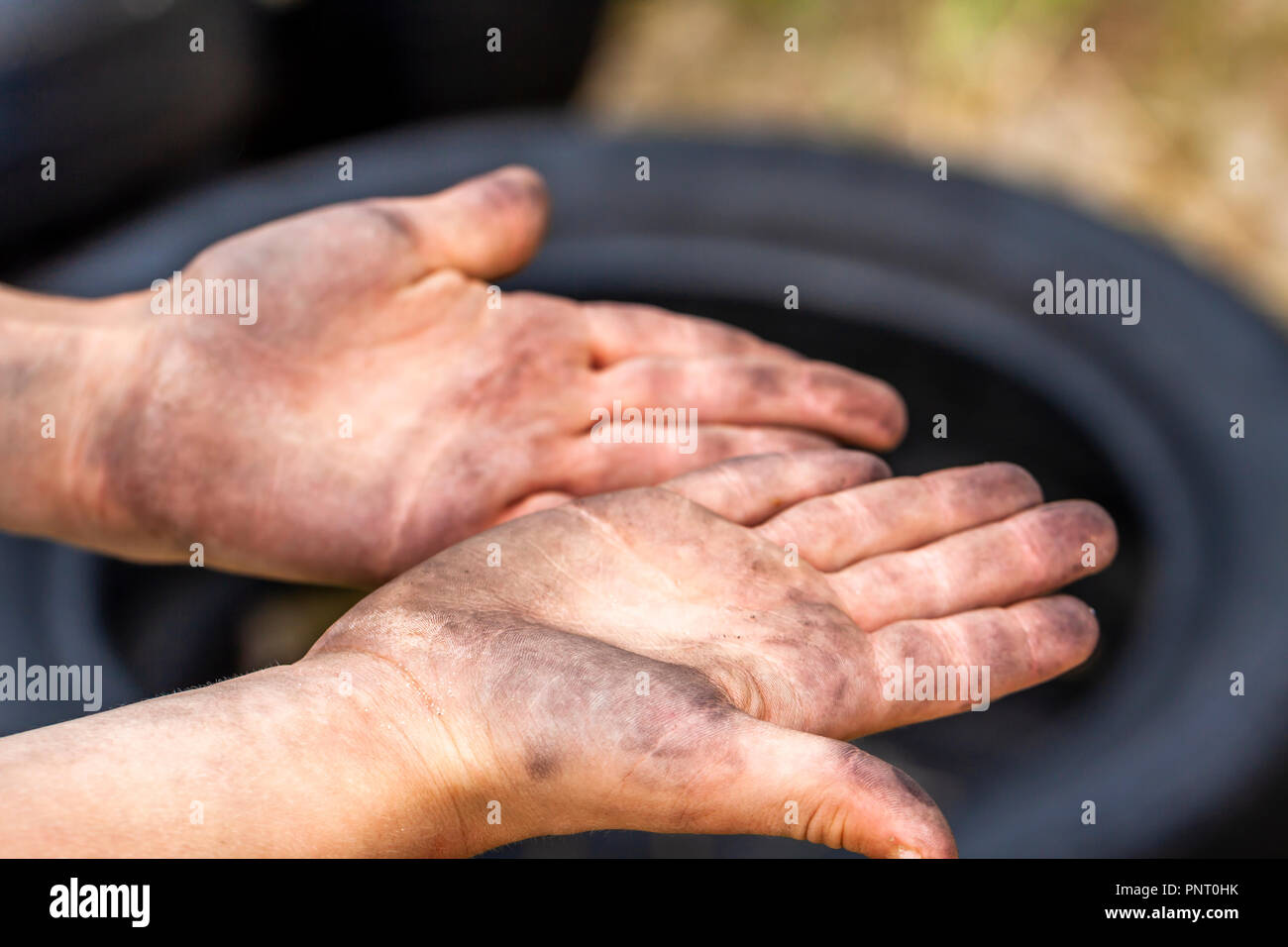 Gros plan du jeune homme les mains sales et le pneu à l'extérieur. Banque D'Images