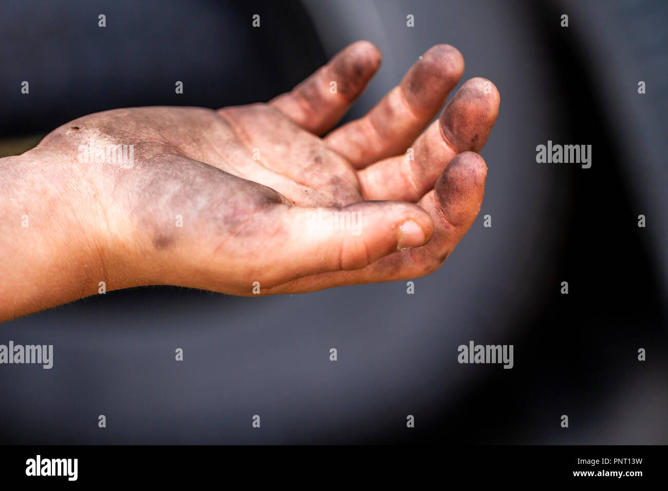 Gros plan du jeune homme les mains sales et le pneu à l'extérieur. Banque D'Images