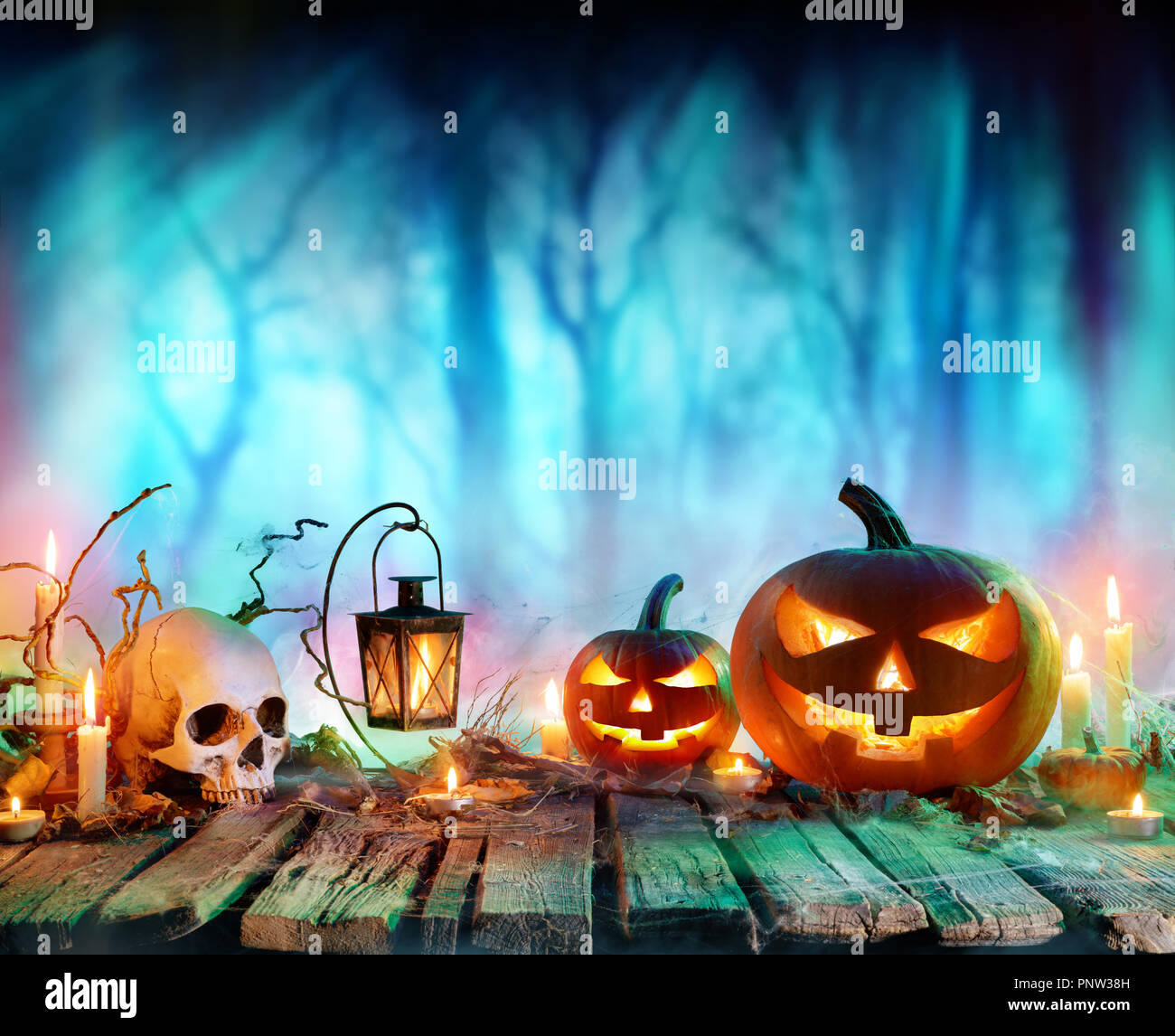 Jack O' lanternes et Bougies sur table en forêt brumeuse - Halloween Background Banque D'Images