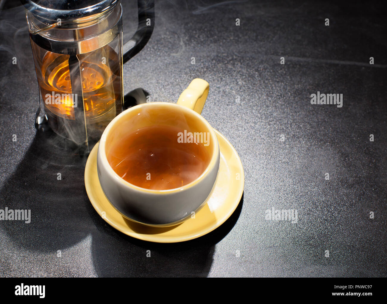 Fumé du thé chaud dans une tasse de thé avec une bouilloire presse Banque D'Images