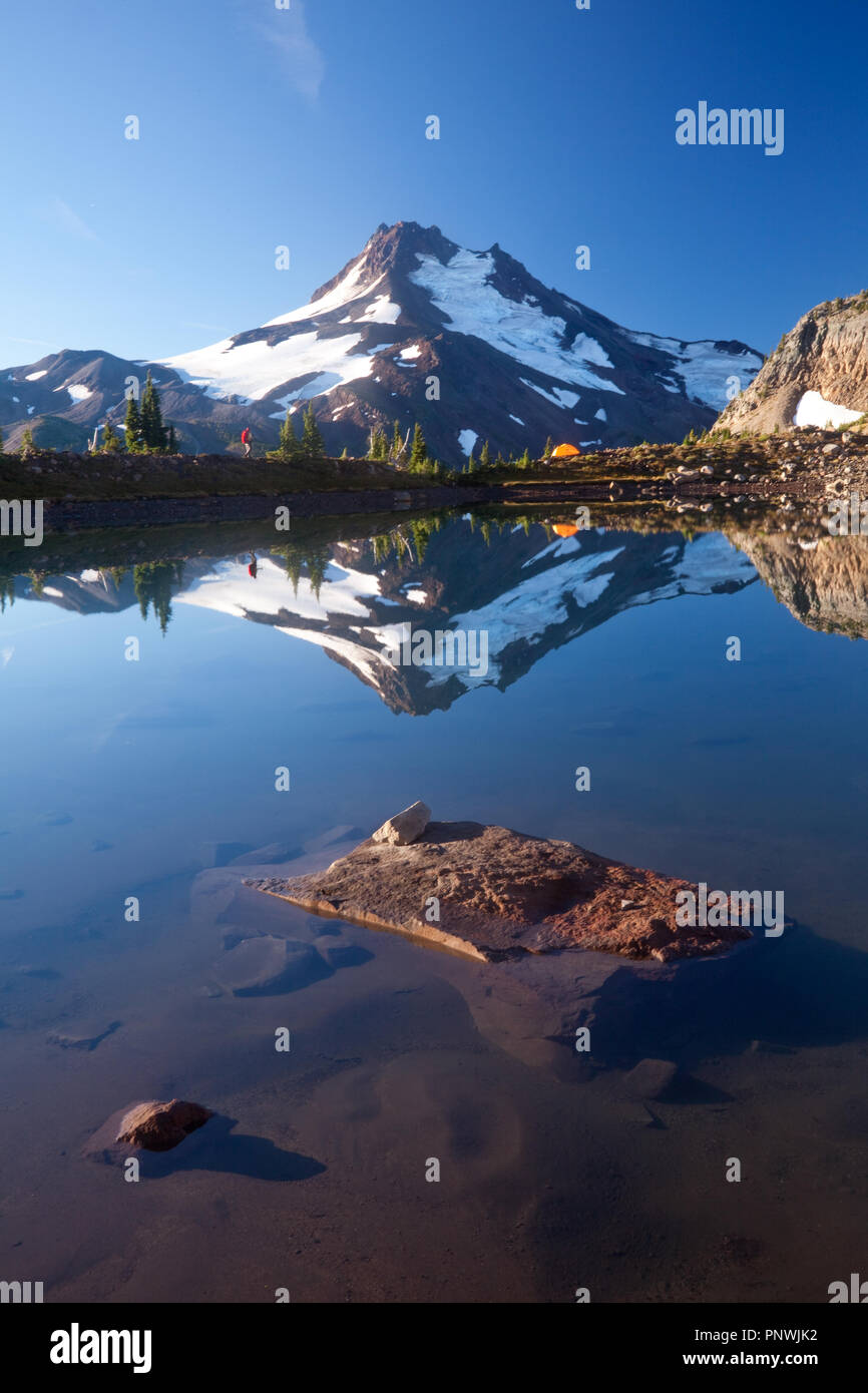 Randonneur et tente avec Mount Jefferson se reflétant dans un lac près de l'arrière-pays de l'Oregon Soeurs Banque D'Images