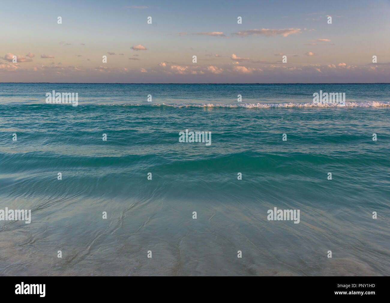 Les eaux bleues de la mer des Caraïbes lap à la plage à Cancun, au Mexique, que la journée se termine. Banque D'Images