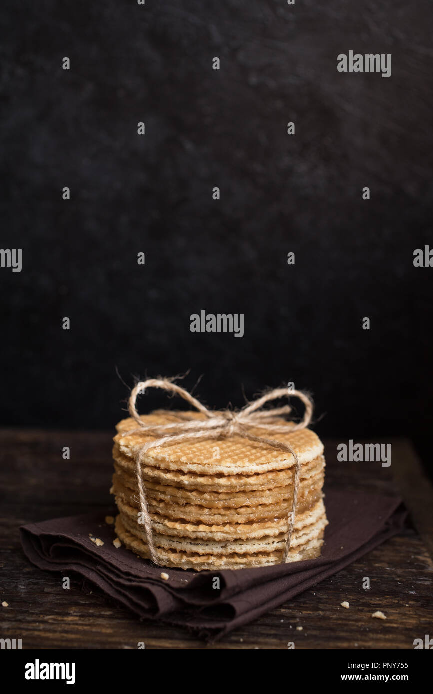 Gaufres néerlandais stroopwafel, avec le caramel. Pile de gaufres néerlandais traditionnels faits maison sur table rustique foncé. Banque D'Images