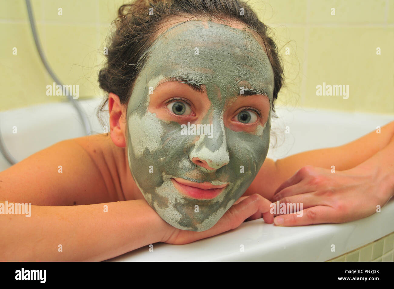 Visage de jeune femme avec un masque de boue dans la baignoire. Banque D'Images