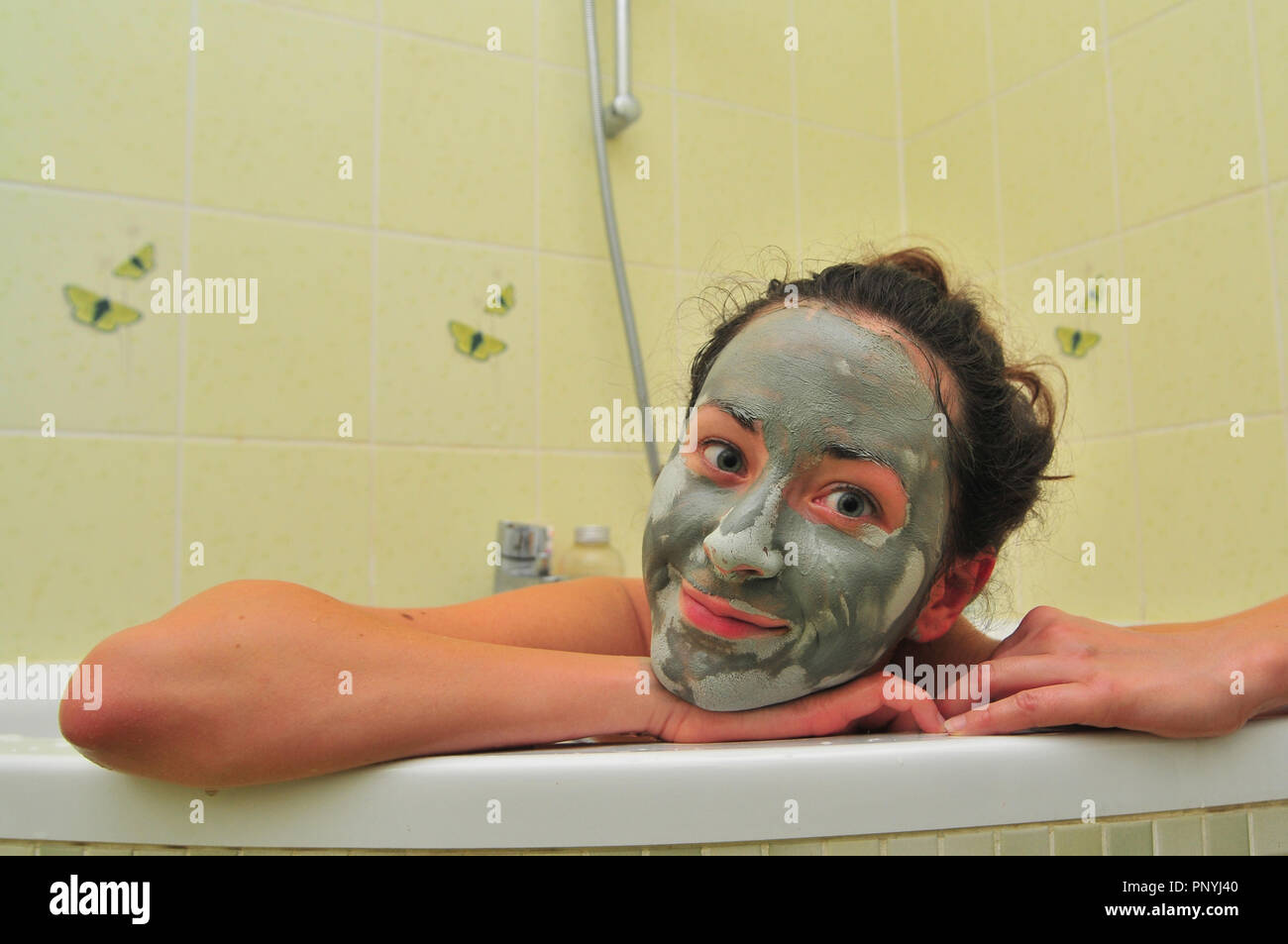 Visage de jeune femme avec un masque de boue dans la baignoire. Banque D'Images