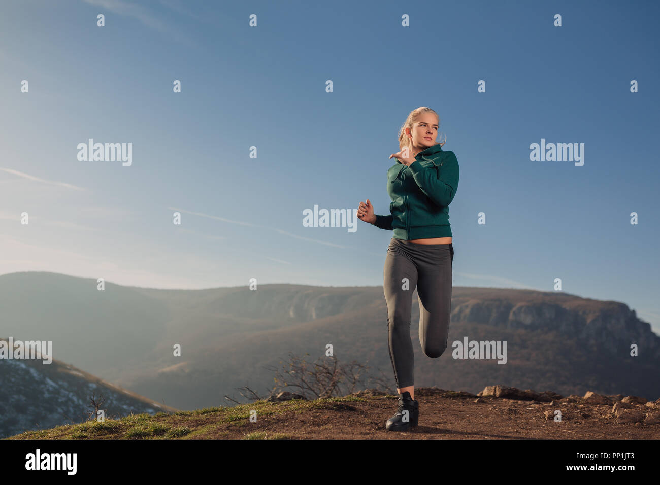 Jeune femme fit courir sur le sommet d'une montagne dans un hoodie Banque D'Images