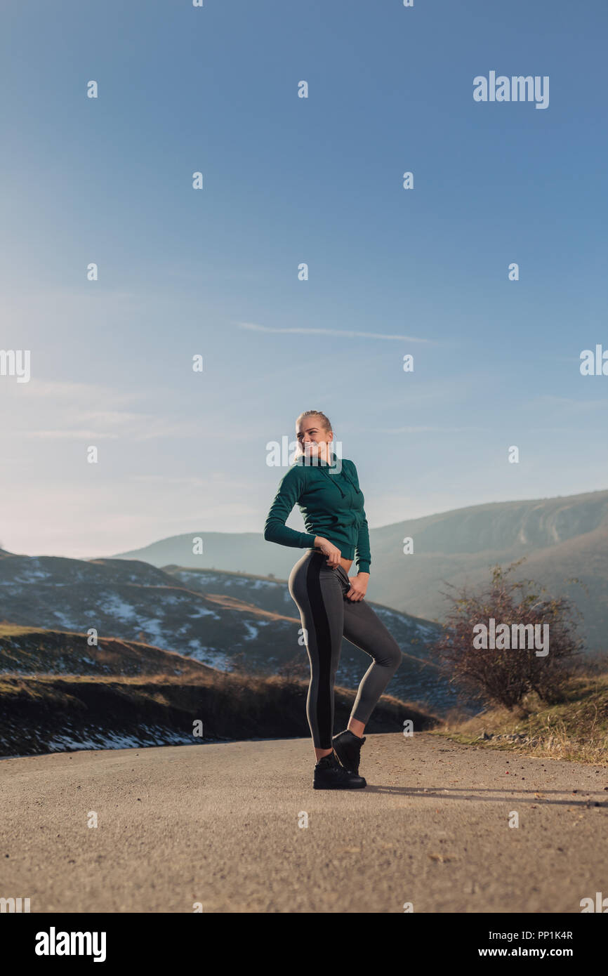 Jeune femme fit l'exercice sur le sommet d'une montagne dans un hoodie Banque D'Images