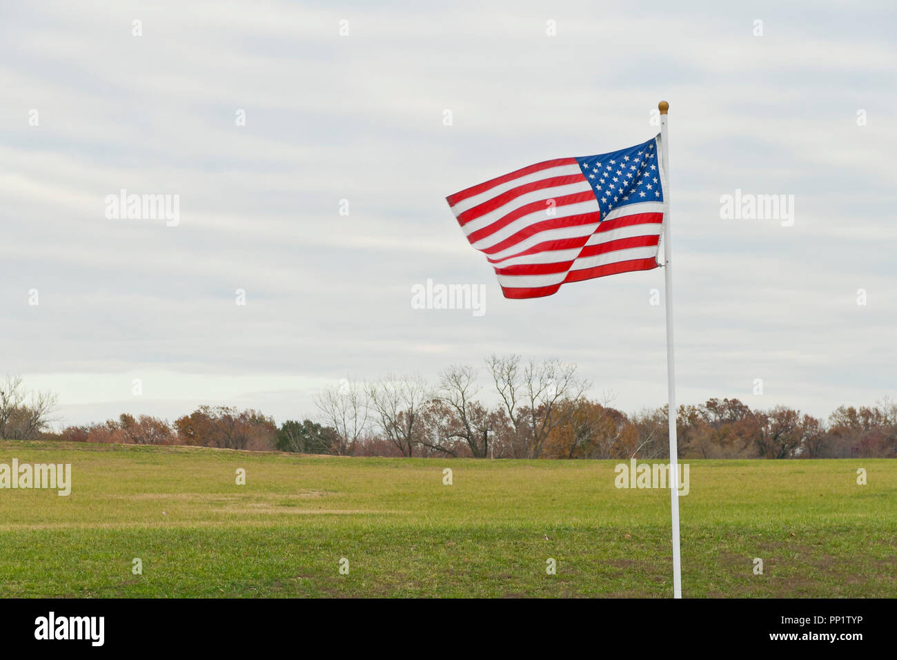 Un drapeau américain vole en l'honneur de la Journée des anciens combattants le long de la route vers le Missouri pour Anciens Combattants sur un ciel nuageux l'après-midi à la fin de l'automne en novembre. Banque D'Images