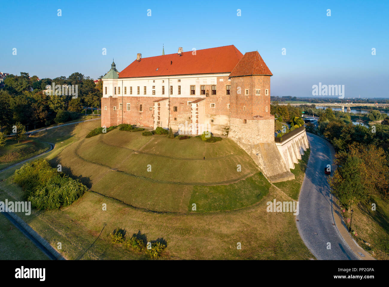 Château gothique médiévale de Sandomierz, Pologne, construit au 14ème siècle. Vue aérienne au coucher du soleil avec la lumière de la rivière Vistule et le pont en arrière-plan Banque D'Images