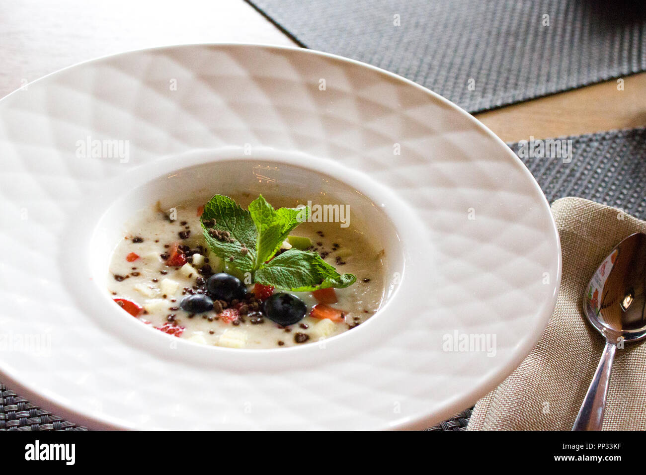 Bon matin, le petit-déjeuner et des aliments sains - concept d'avoine porridge savoureux avec des fraises, les feuilles de menthe, de bleuets et de chocolat en blanc bol plat Banque D'Images