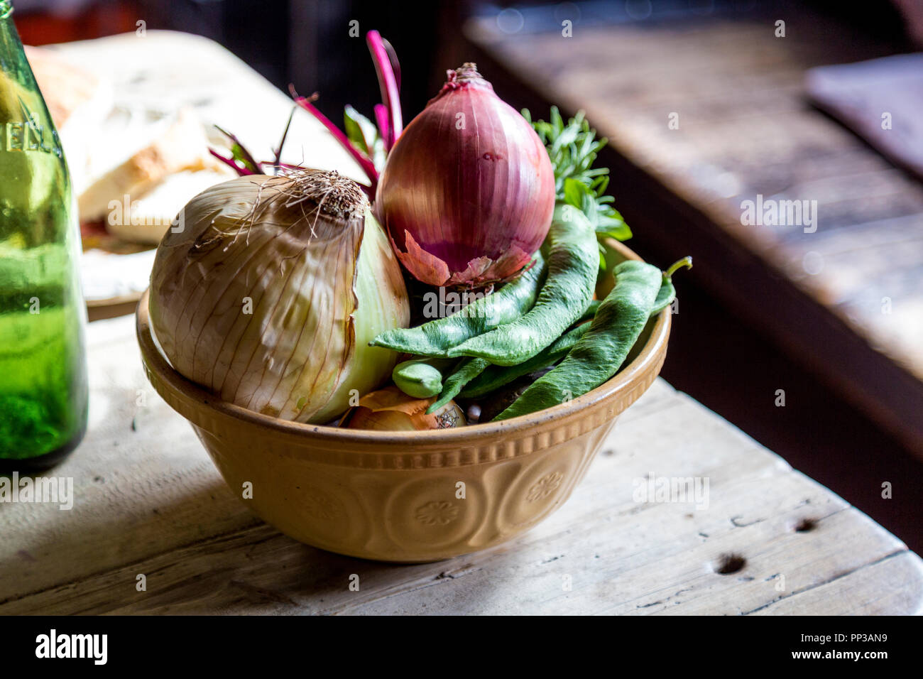 Bol rustique de légumes, les oignons et les haricots sur une table en bois dans une ancienne cuisine (Black Country Living Museum, Dudley, UK) Banque D'Images