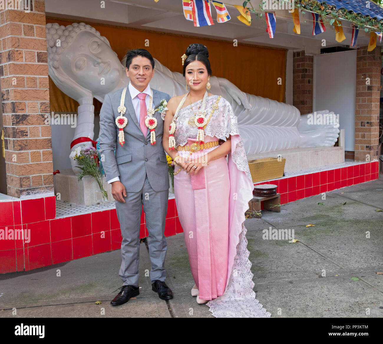 Portrait, en face d'une statue de Buddah. de mariée Thaï & son fiancé de l'Amérique du Sud juste après leur mariage bouddhiste à Elmhurst, Queens, New York. Banque D'Images