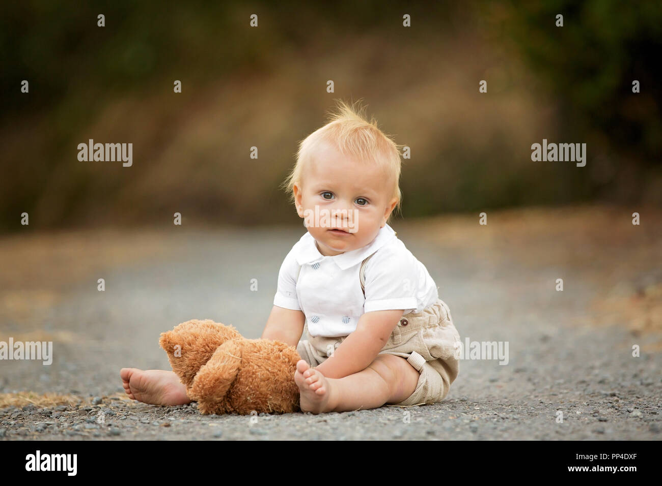 Beau garçon élégant tout-petit enfant drôle de visage avec bretelles en  jouant au printemps ou en été, Jardin, parc et nourrir son ours en peluche  Photo Stock - Alamy