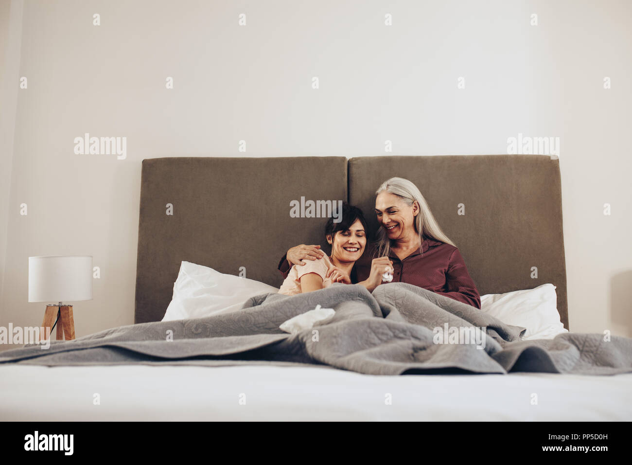 Femme âgée parle à sa fille assis sur le lit à la maison. Jeune femme passer du temps avec sa vieille mère. Banque D'Images