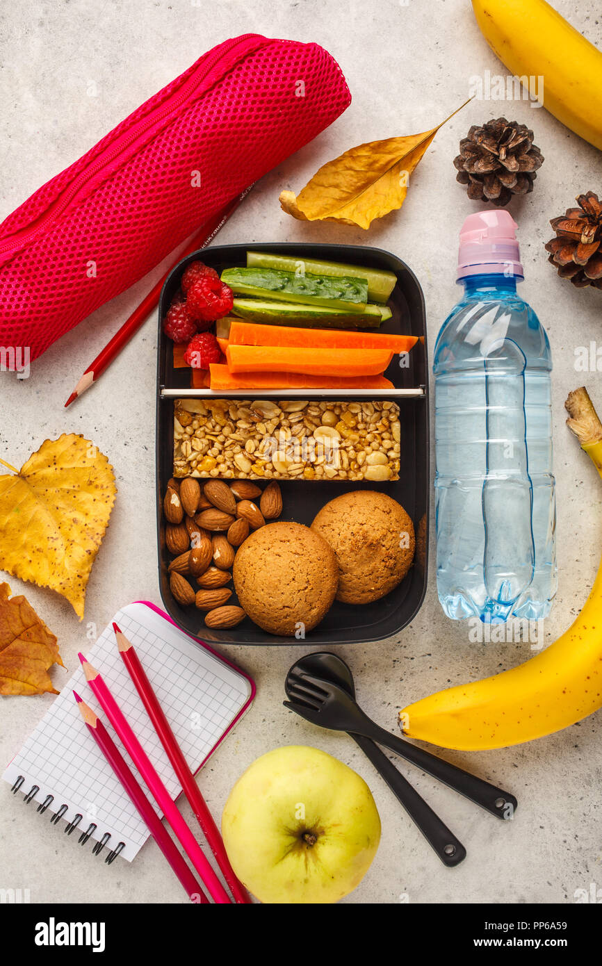 Préparation des repas sains avec des contenants des fruits, des baies, des collations et des légumes. La nourriture à emporter sur fond blanc, vue du dessus. Boîte à lunch à l'école. Banque D'Images