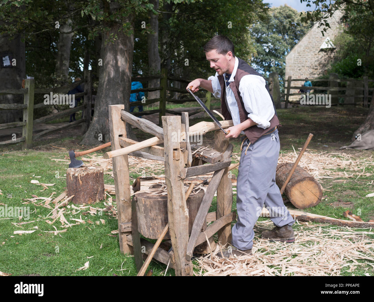 Carpenter en utilisant drawknife et cheval de rasage pour faire un poteau de clôture en chêne, Beamish Museum, Co Durham, England, UK Banque D'Images