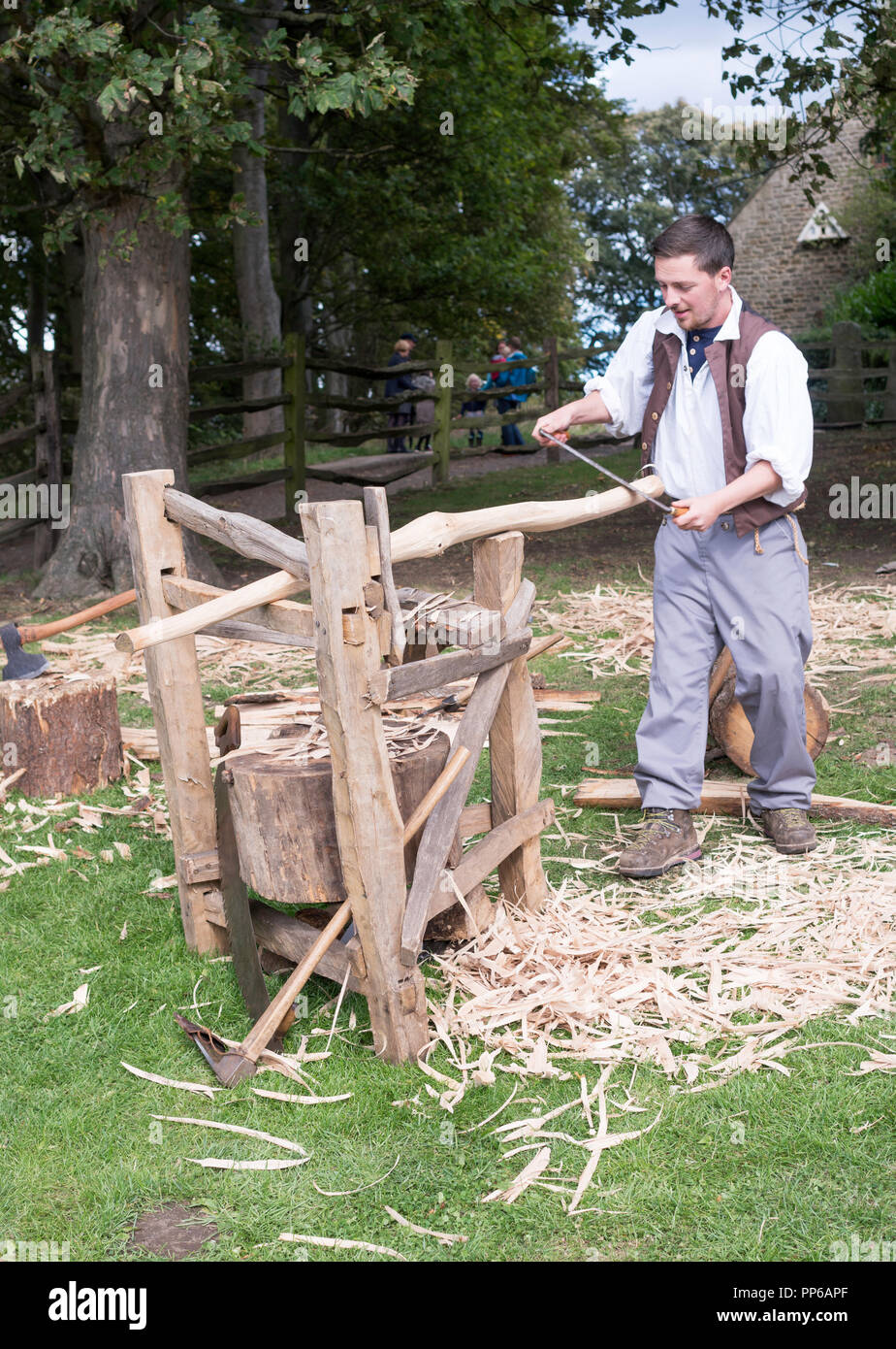 Carpenter en utilisant drawknife et cheval de rasage pour faire un poteau de clôture en chêne, Beamish Museum, Co Durham, England, UK Banque D'Images