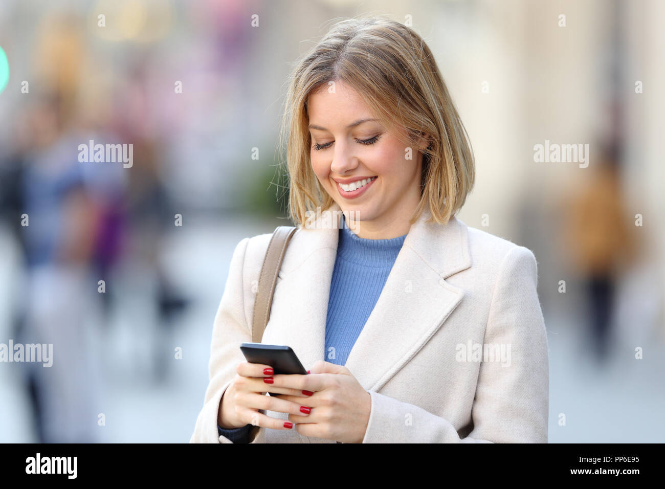 Portrait d'une femme élégante en utilisant un téléphone intelligent en marchant dans la rue Banque D'Images