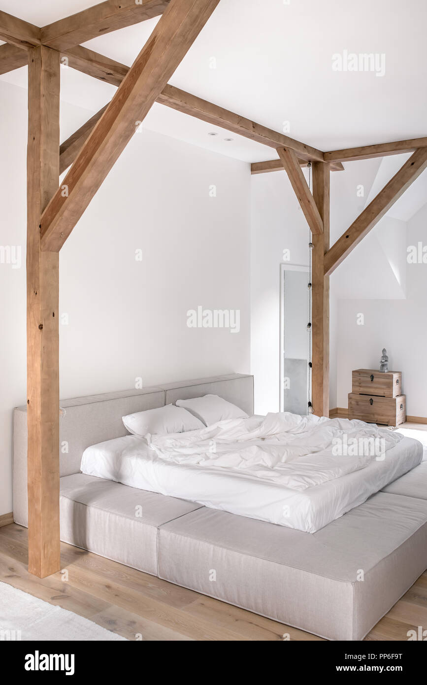 Chambre à coucher moderne avec des murs blancs, des poutres apparentes ...