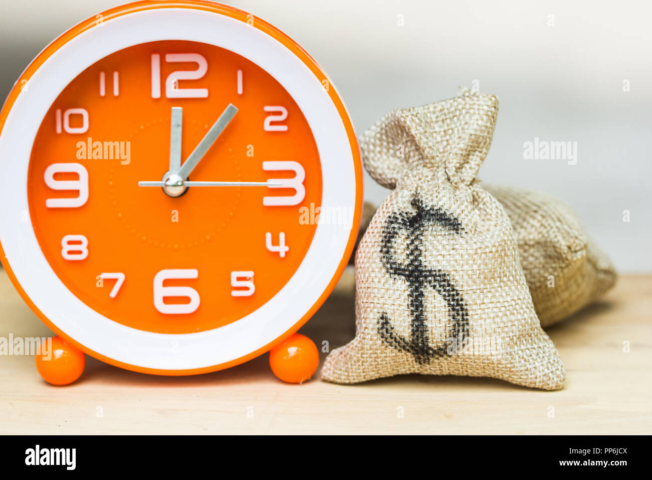 Utiliser l'investissement de l'argent pour gagner du temps et des ressources concept. US dollar dans escarcelle avec orange blanc sur fond d'horloge de table en bois. Démontrer le gro Banque D'Images