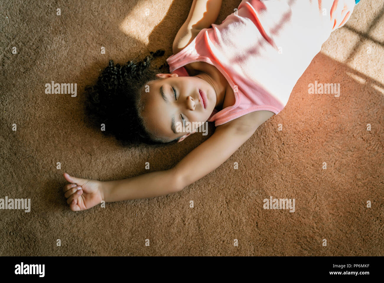 Girl laying on salon tapis dans la lumière du soleil Banque D'Images