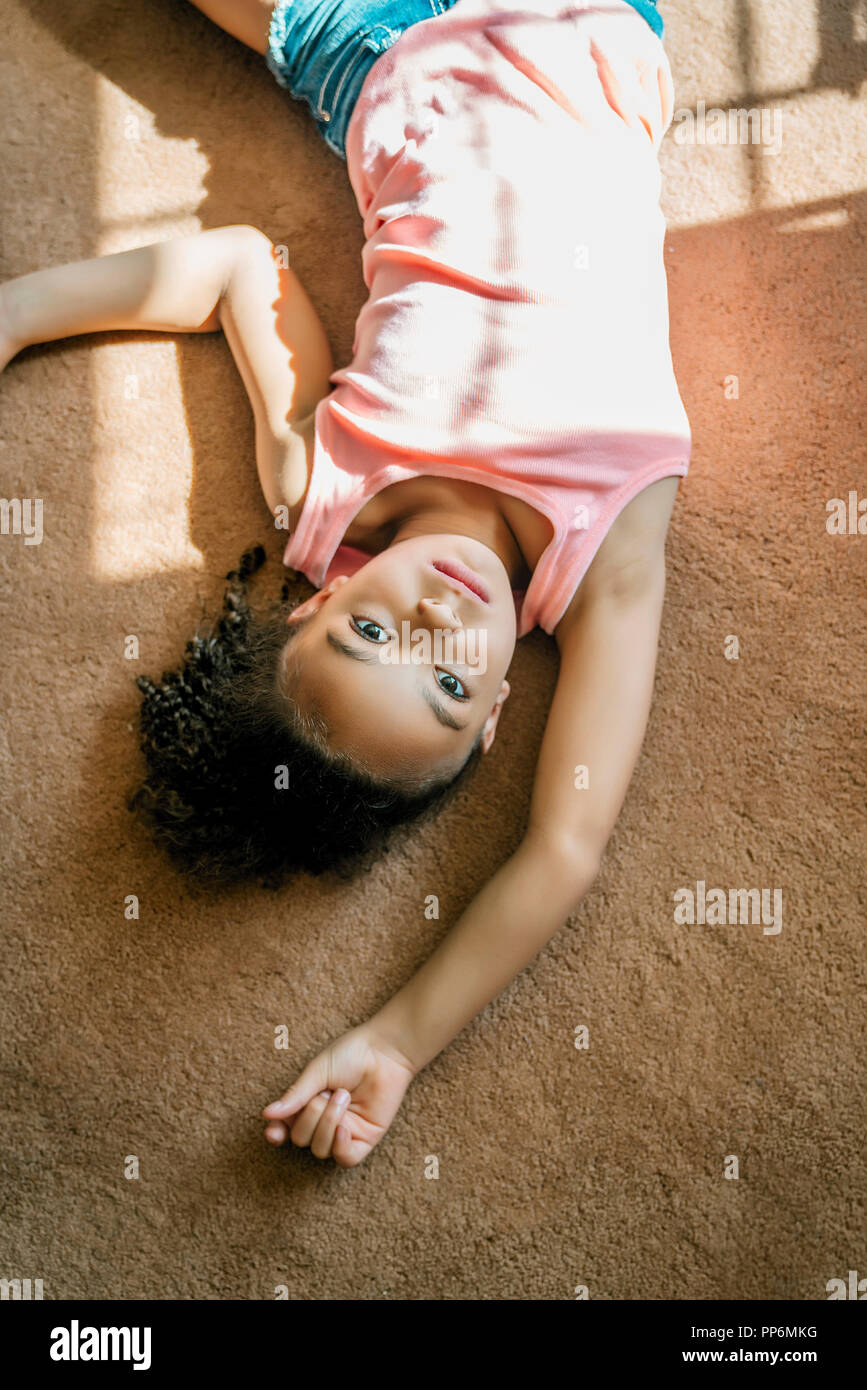 Girl laying on salon tapis dans la lumière du soleil Banque D'Images
