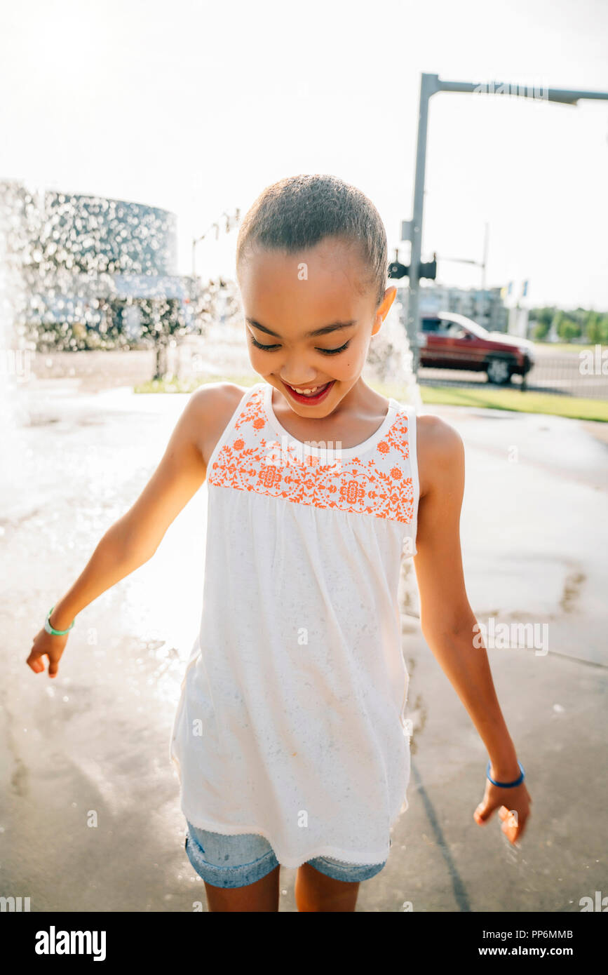 Smiling girl playing in fontaine publique en été Banque D'Images