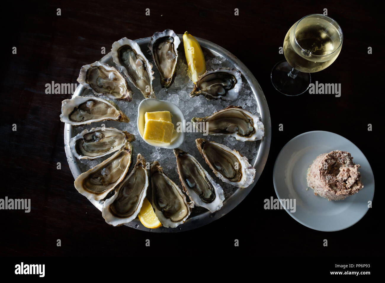 Une assiette d'huîtres du bassin d'Arcachon. Les huîtres sur un lit de glace au citron, beurre, un verre de vin et quelques pate Banque D'Images
