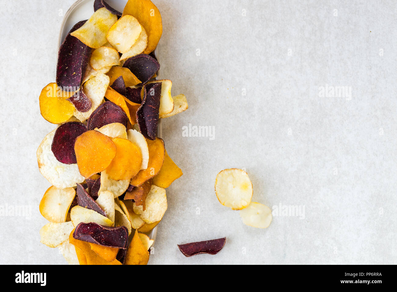 Bol de collation saine de croustilles de légumes, tels que la patate douce, betterave, carotte, panais sur fond gris clair Banque D'Images